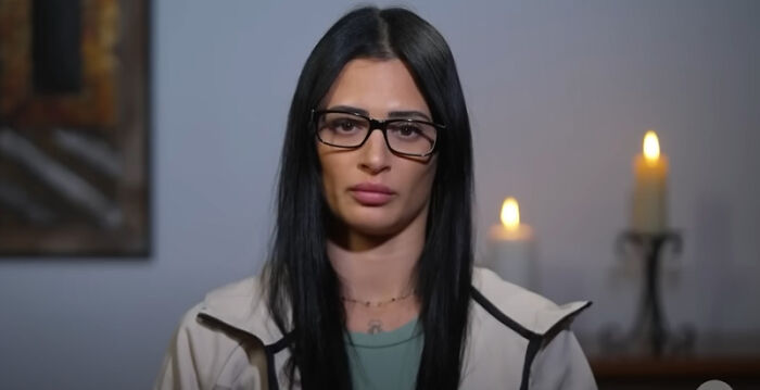 Young woman with glasses and long black hair speaking about DHS response to agents jailing and deporting Aussie bride incident