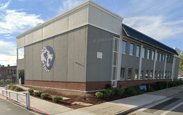 School building exterior under blue sky, associated with teen identified as killer in decades-old cold case investigation.