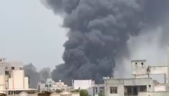 Thick black smoke rising over buildings after Air India flight crash moments after take-off.
