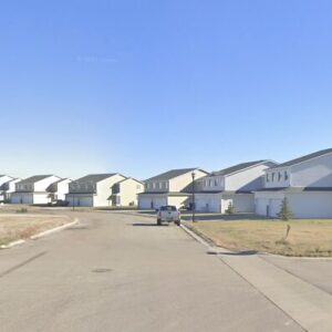 Suburban neighborhood street with single-family homes under a clear blue sky related to foster parents case.