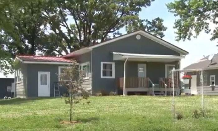 Small gray house with porch on grassy lawn and large trees, related to police rescue of children from Bible study camp.