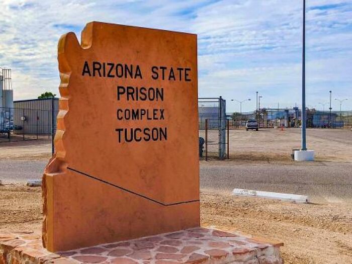 Arizona State Prison Complex Tucson entrance sign under blue sky, related to violent prison death of killer dad case.