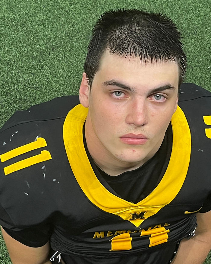 Teen athlete wearing black and yellow football uniform sitting on turf, related to Karmelo Anthony stabbing case.