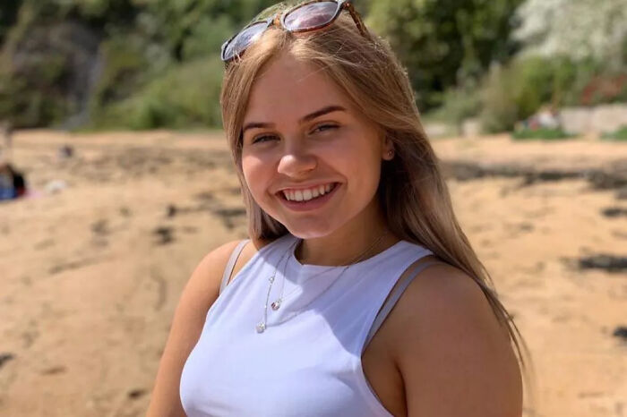 Young woman smiling at the beach, related to man accessed porn 170 times during murder and cover-up investigation.