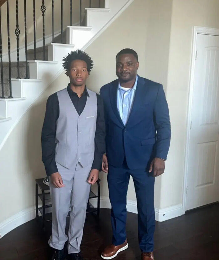 Two men standing indoors near stairs, one in a gray vest and black shirt, the other in a blue suit, related to Karmelo Anthony case.
