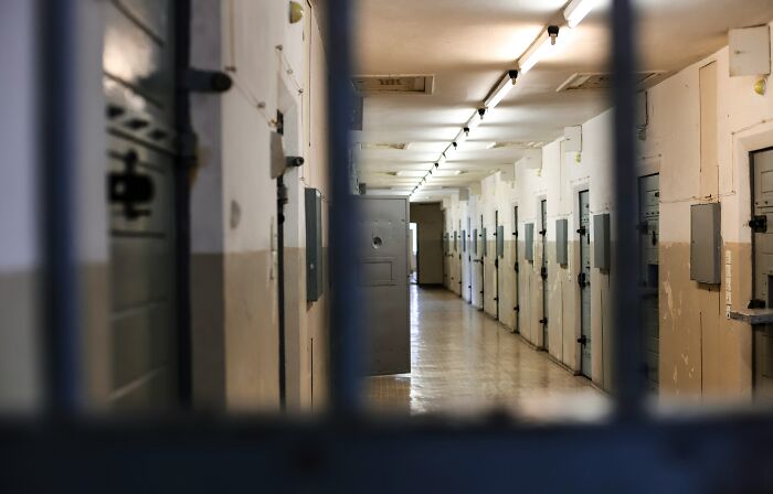 Prison hallway with closed cell doors and dim lighting, symbolizing teen beat incidents and police investigation.