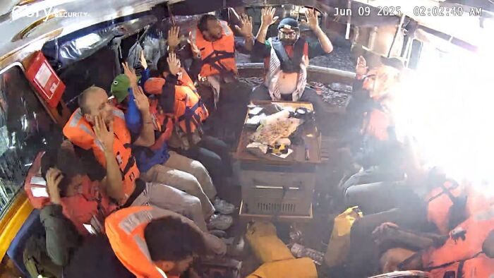 Passengers wearing life jackets raising hands inside a boat during Israel interception of Gaza-bound freedom flotilla event.