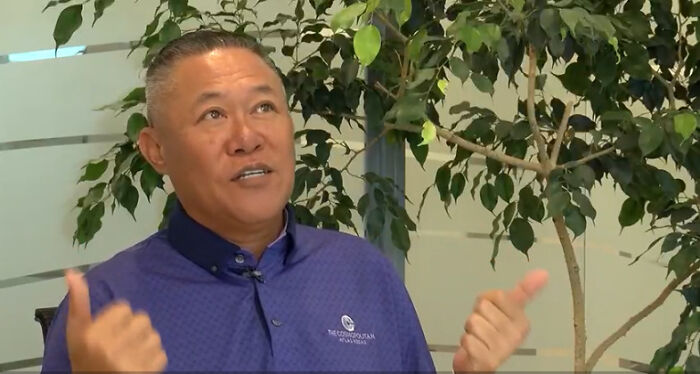 Man in purple shirt speaking indoors near a large plant, representing ICE forces purple heart veteran self-deport story.