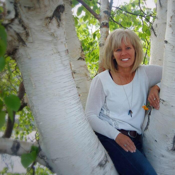 Woman sitting among birch trees outdoors, representing Nevada teacher accused of sexually abusing children.