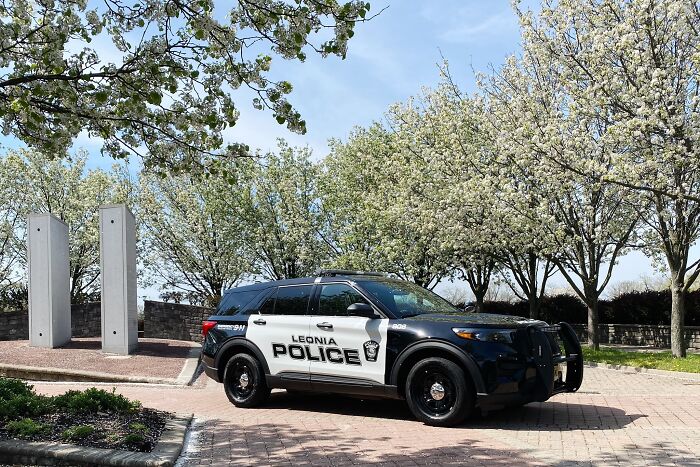 Leonia police vehicle parked near blooming trees representing NJ police chief involved in abuse allegations.