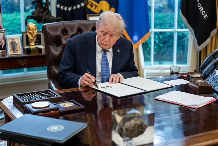 Donald Trump in the Oval Office signing documents related to federal judge blocking asylum shutdown at U.S.-Mexico border.