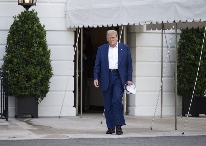 Donald Trump walking outside a building in a blue suit, related to new audio of threatening to bomb Moscow.