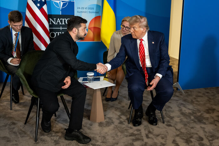 Donald Trump shaking hands with Volodymyr Zelenskyy amid Ukraine arms discussion and Putin relations concerns.