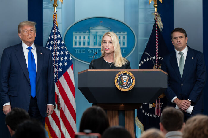 Donald Trump with officials at White House podium during press briefing on Epstein files report claims.
