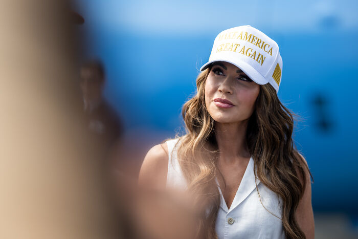 Woman wearing Make America Great Again hat in outdoor setting, related to Kristi Noem and Texas flood aid delay claims.