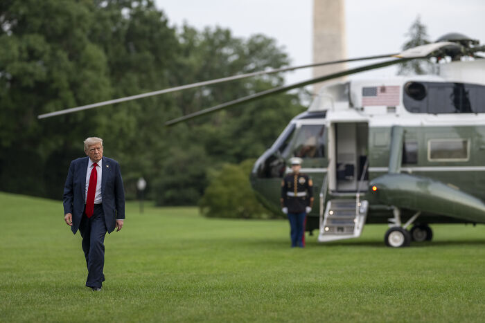 Former President Trump walking on grass near helicopter, illustrating why Trump won&rsquo;t distance himself from Putin amid Ukraine arms shift.