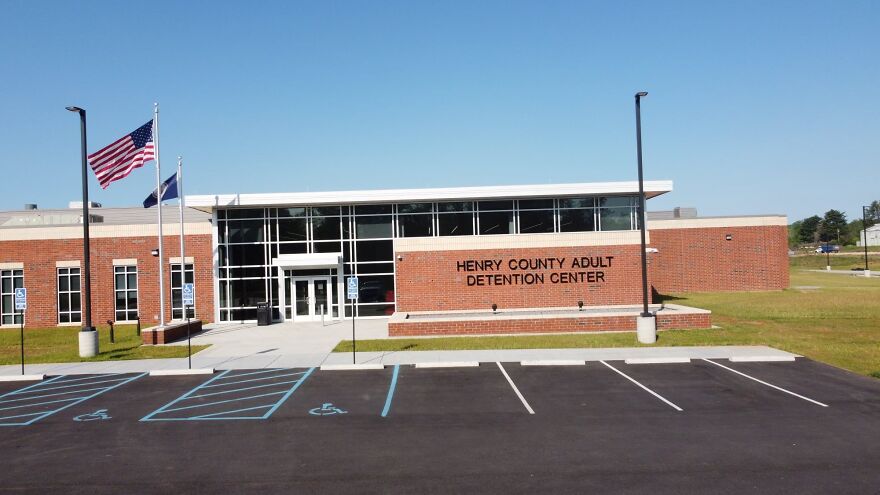 Exterior of Henry County Adult Detention Center with clear sky and empty handicap parking spaces in front.