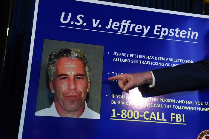 Photo showing a government presentation board highlighting Epstein client list and FBI contact details during U.S. case.