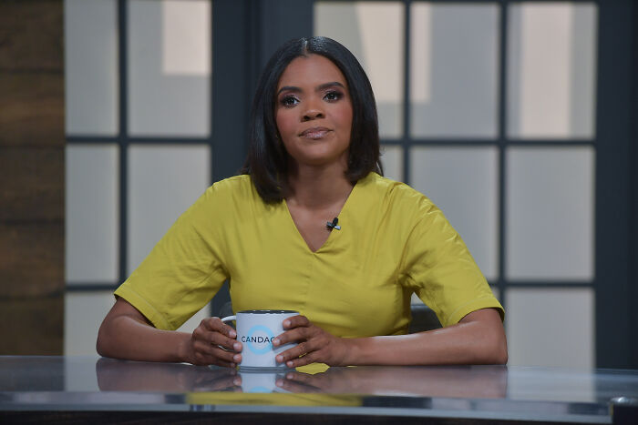 Candace Owens seated at a desk holding a mug during a televised discussion about Macron court claims.