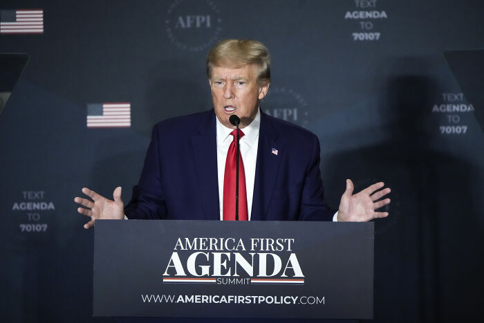 Donald Trump speaking at America First Agenda Summit with old accusations gaining darker context in Epstein-related discussions.