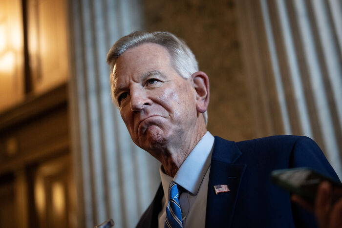 GOP senator in a suit with American flag pin speaking inside a government building about Trump cankles and left-wing opposition.