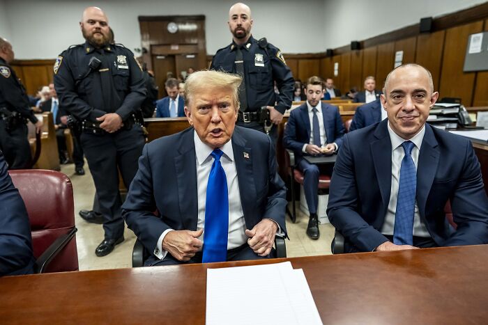 Emil Bove seated in courtroom with Donald Trump and police officers during judicial confirmation hearing session