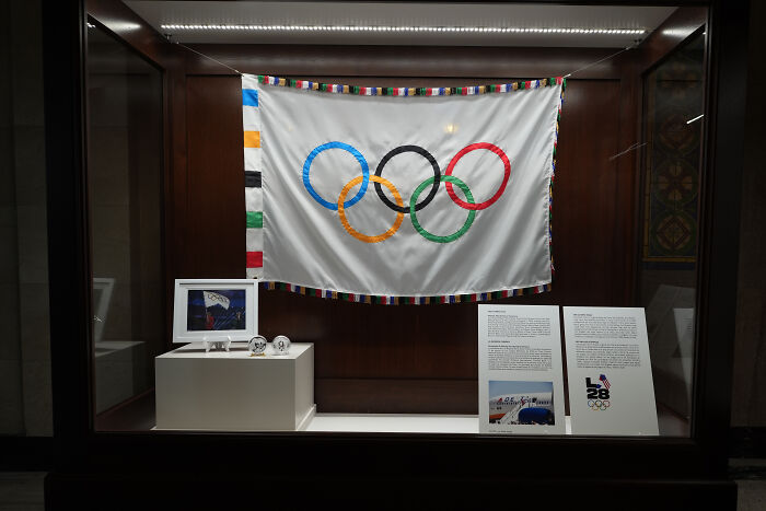 Olympic flag with five rings displayed in a wooden case highlighting U.S. Olympic Committee transgender athlete ban in women&rsquo;s sports.