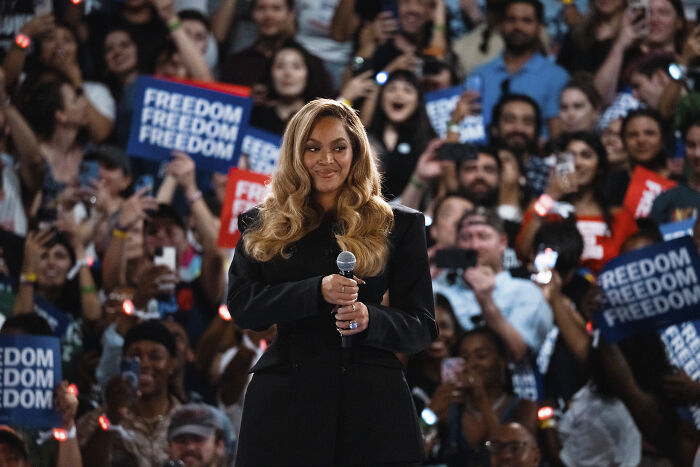 Beyonc&eacute; holding microphone at rally with crowd, related to Donald Trump blasting and prosecution over Kamala Harris support.