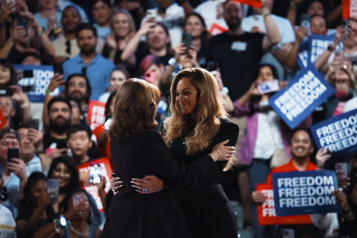 Beyonc&eacute; embracing a woman at an event with crowd holding freedom signs, related to Donald Trump and Kamala Harris support controversy.