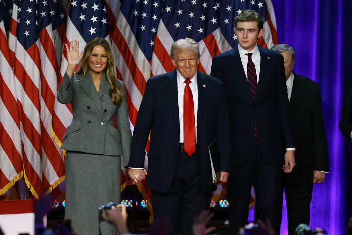 Barron Trump standing with parents at an event, representing U.S. citizenship discussion and family debate.