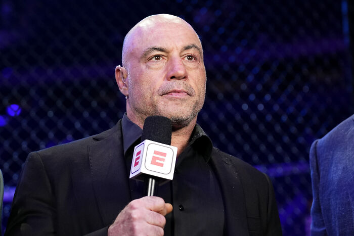 Joe Rogan speaking into ESPN microphone at event, addressing ICE raids controversy during broadcast.