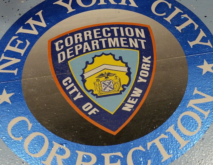 New York City Correction Department emblem on a floor representing systemic dysfunction at Rikers Island facility.