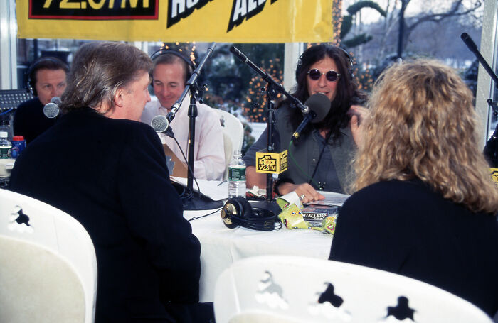Donald Trump speaking during a Howard Stern radio show broadcast, with microphones and hosts at an outdoor setup.