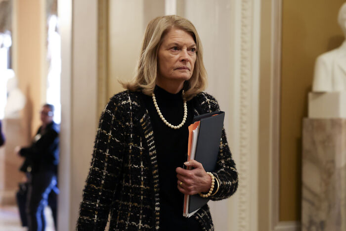 Woman in formal attire holding files in a hallway, related to Senate confirmation of Trump enforcer Emil Bove for judge role