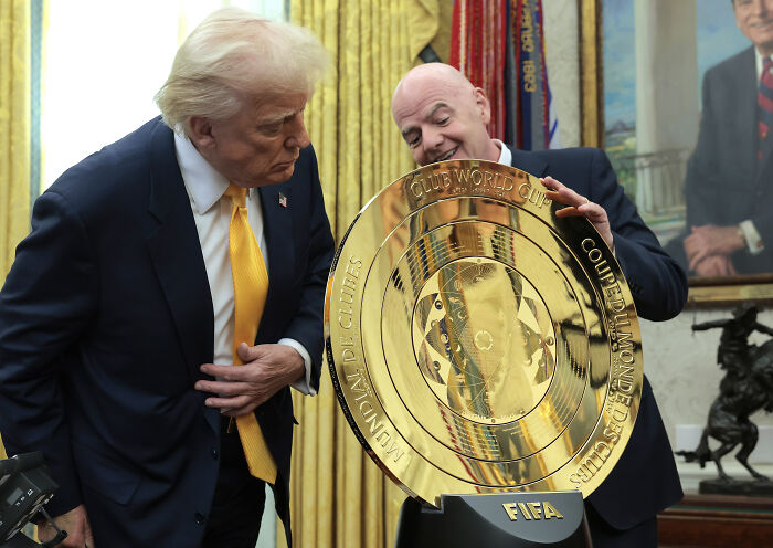 Donald Trump and FIFA president with the Gold Club World Cup trophy in a formal room setting.