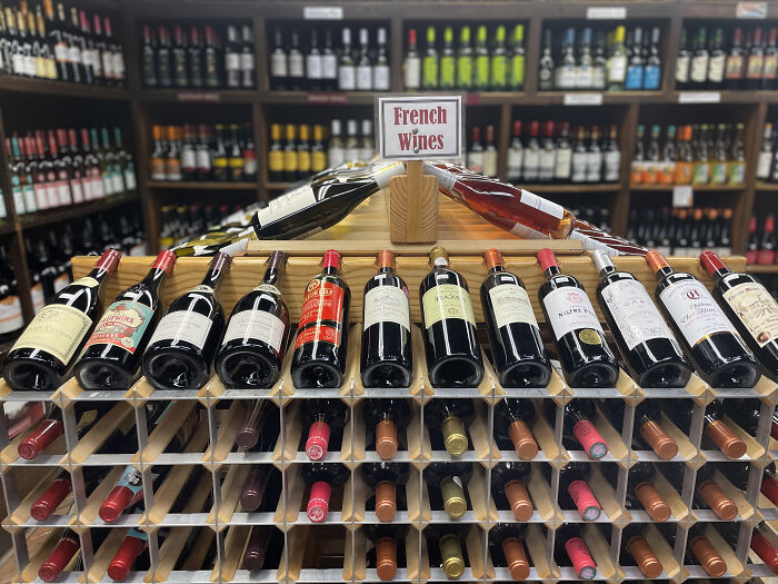 French wines displayed in a store with shelves of bottles, highlighting European products amid new tariffs concerns.