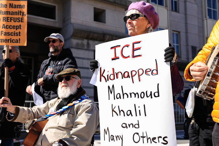 Activist holding a sign demanding accountability for Mahmoud Khalil's ICE detention and $20M Trump claim.