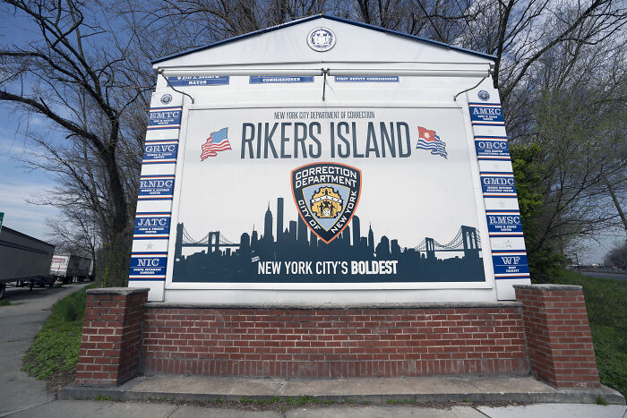 Rikers Island Correction Department sign with city skyline, highlighting systemic dysfunction at Rikers Island in inmate context.