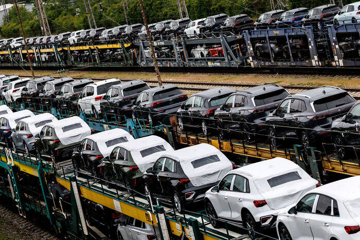 Rows of new European cars loaded on train carriers, highlighting potential impact of shocking tariffs on car affordability.