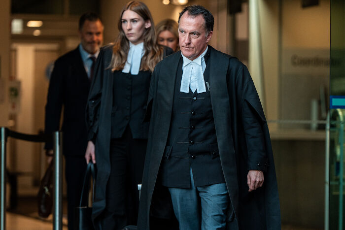 Lawyers in formal robes walking through courthouse hallway after guilty verdict in mushroom poisoning case.