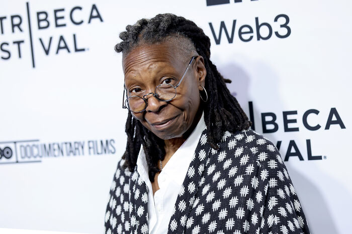 Whoopi Goldberg at Tribeca Festival wearing glasses and patterned jacket, captured during a candid moment.