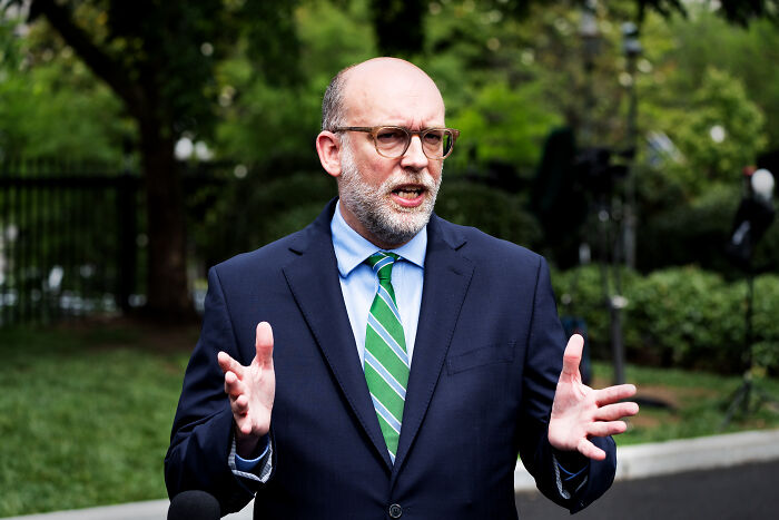 Man in suit and glasses speaking outdoors about Senate cutting billions in foreign aid and public broadcasting funds.