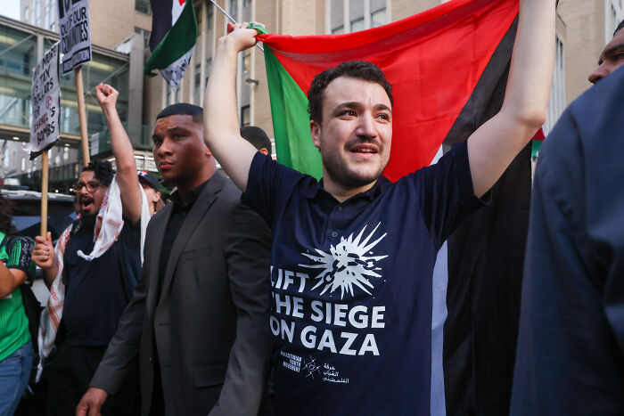 Activist Mahmoud Khalil holding a flag during a protest demanding accountability after ICE detention and Trump claim.
