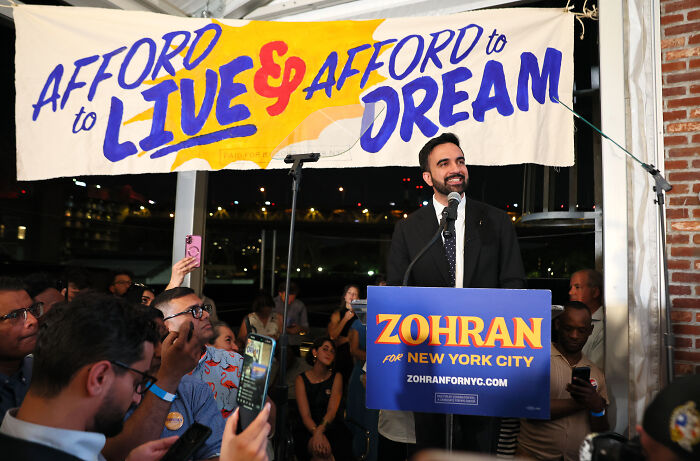 NYC mayoral nominee Zohran addressing crowd at campaign event amid accusations of being a communist by Trump.