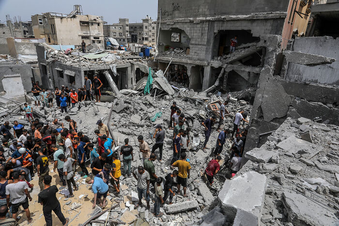 Crowd gathers among rubble and destroyed buildings after bombing, highlighting aftermath of Netanyahu Trump Nobel Peace Prize nomination.