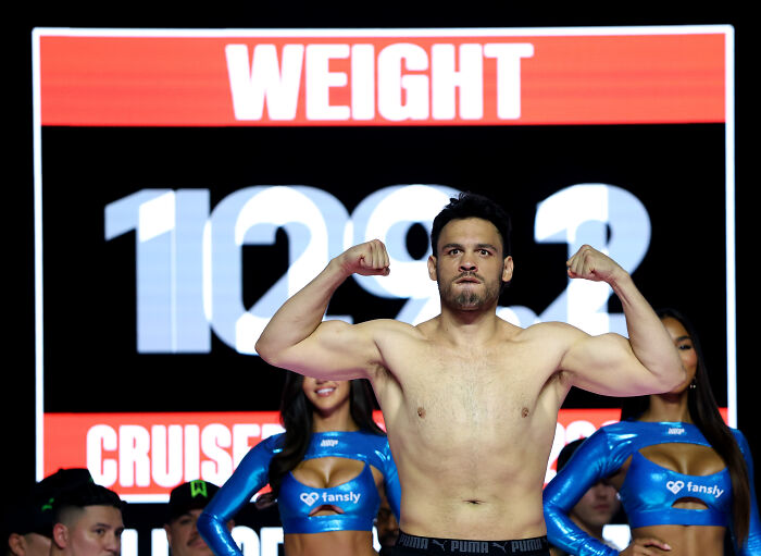 Boxing champion flexing muscles at weigh-in event, linked to gun case and notorious cartel investigations by ICE.