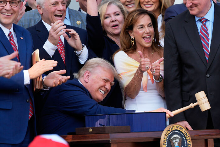 Group of lawmakers applauding as Donald Trump signs a bill with Josh Hawley pushing Medicaid cuts reversal efforts.