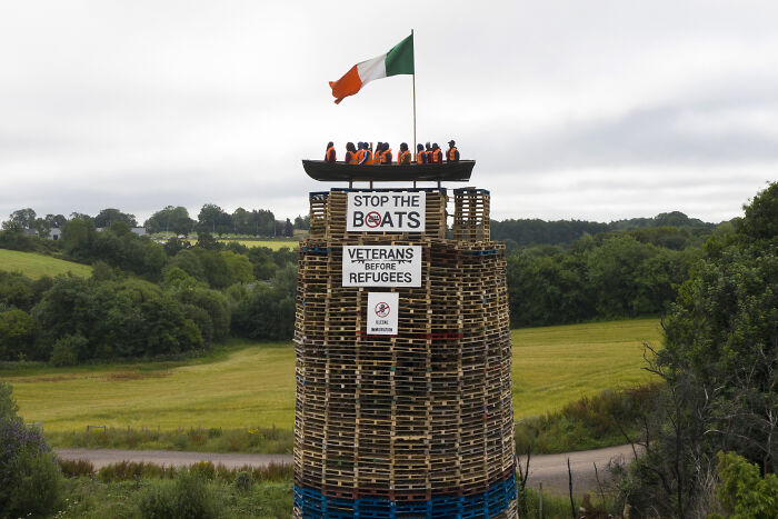 Bonfire with mock migrant boat and anti-refugee signs set alight sparking outrage over racist display.