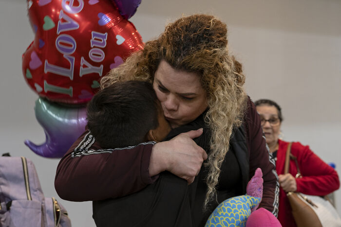A woman hugging a child tightly, expressing fear of separation affecting immigrant families and self-deport choices.