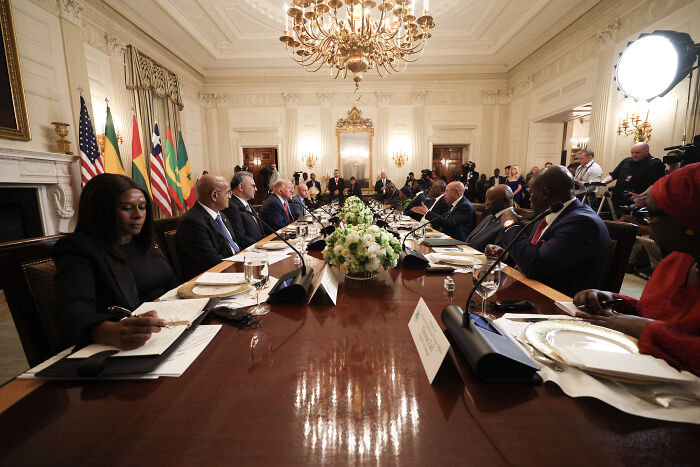 Leaders seated around a large table in a formal meeting room discussing issues related to Trump's comment on Liberian President's English.